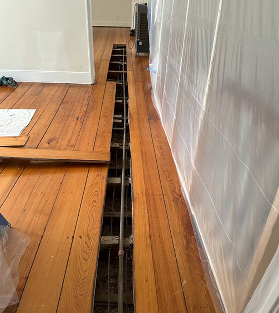 Open floorboards with plastic sheeting